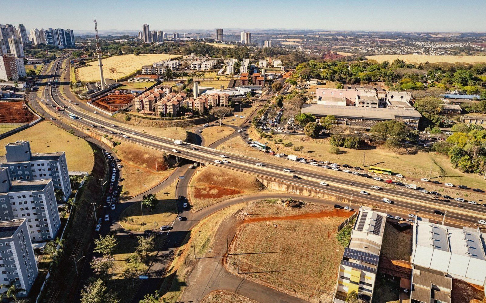 Aerial view of a highway overpass and busy roundabout amid urban buildings and open lots